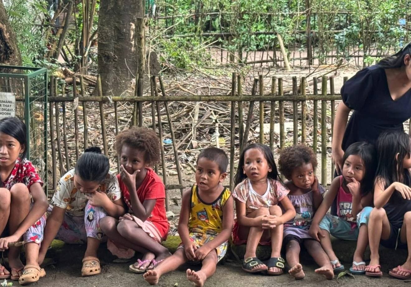 Children sitting together outdoors at a sponsorship program gathering