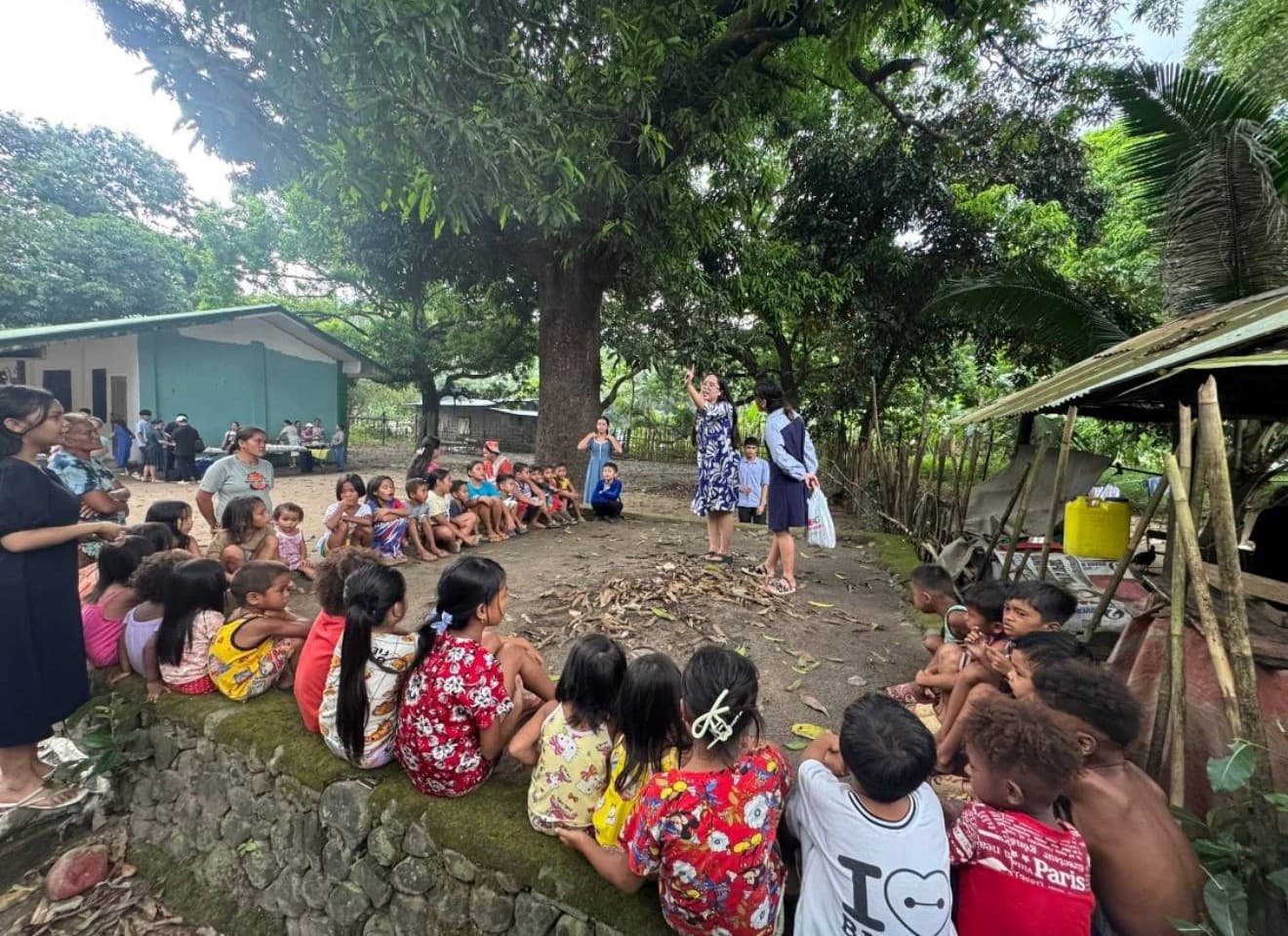 Children seated in a circle outdoors during a sponsorship program activity