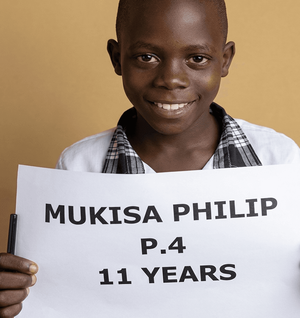 Sponsored student in a school uniform smiling with a name sign